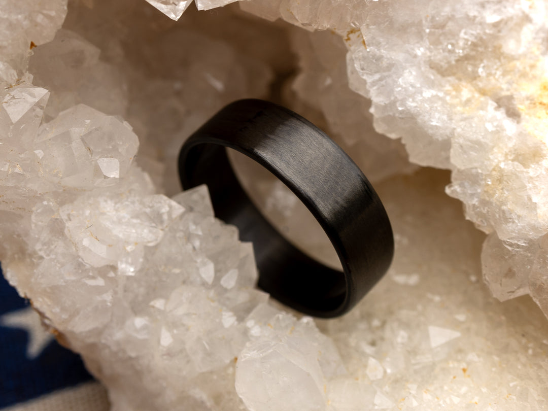 6mm uni-directional carbon fiber ring with matte finish, displayed in a crystal geode setting.