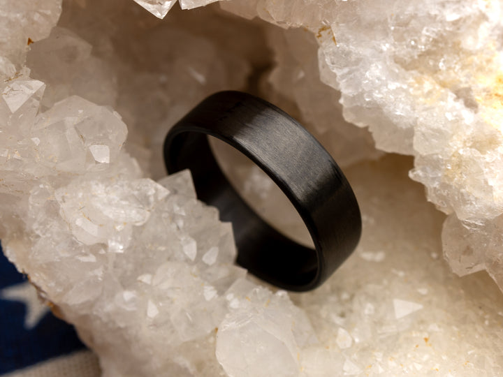 6mm uni-directional carbon fiber ring with matte finish, displayed in a crystal geode setting.