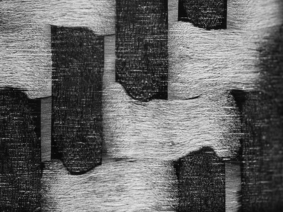 Macro close-up of classic 3K carbon fiber twill weave, showing bold woven structure and matte texture