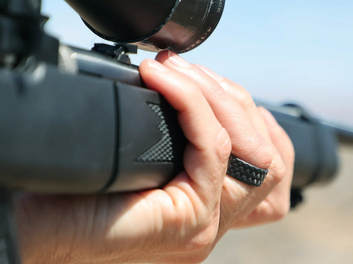 Close-up of the Vertex ring worn while gripping a rifle, demonstrating its rugged design and comfort during active use.