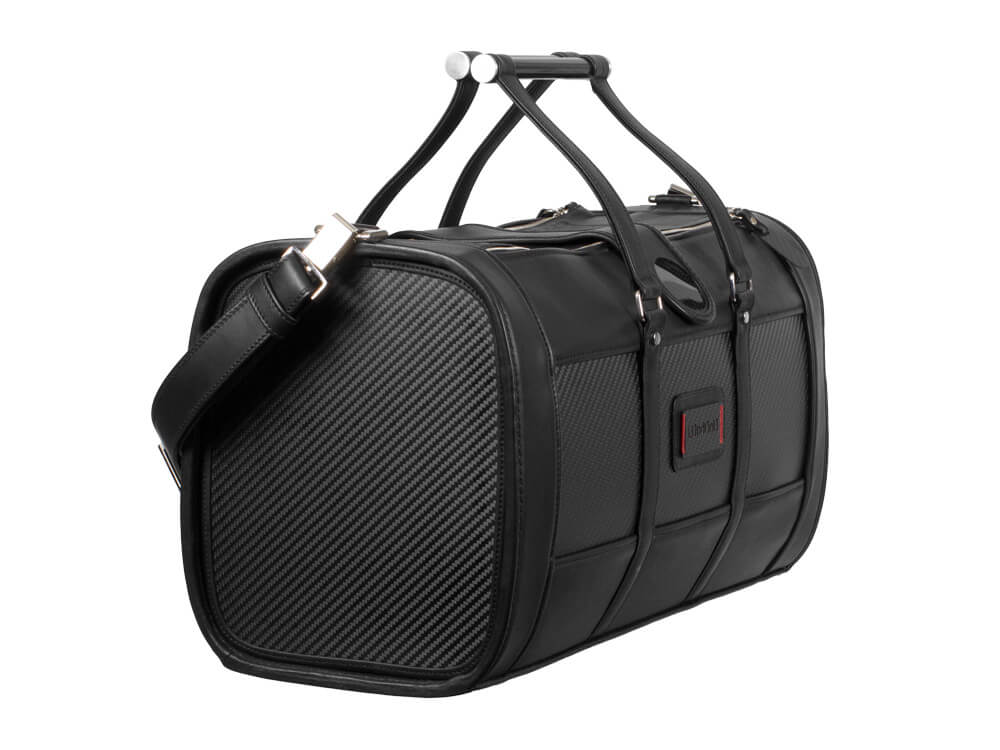 Three-quarter view of a premium leather and carbon fiber weekend bag with detachable shoulder strap.