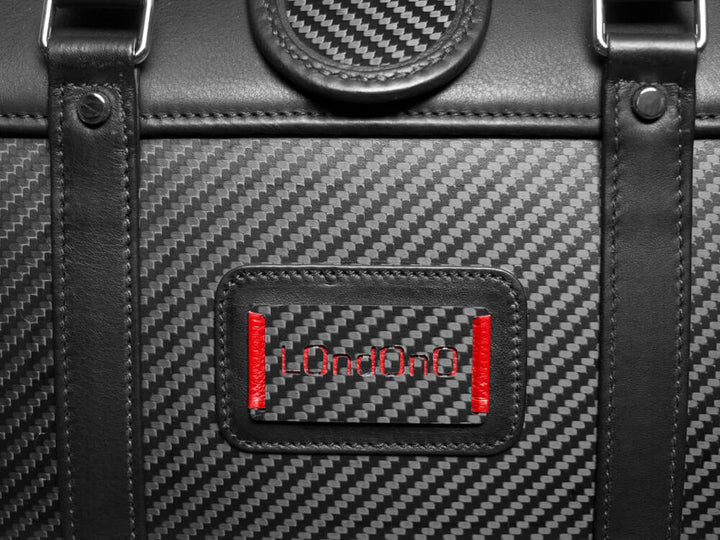 Close-up of the Londono logo on a carbon fiber inlaid panel on a high-end leather weekend bag.