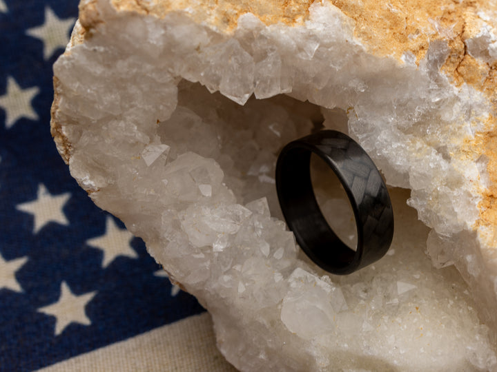 Carbon fiber ring with 45° weave in crystal geode, placed over American flag backdrop for patriotic styling