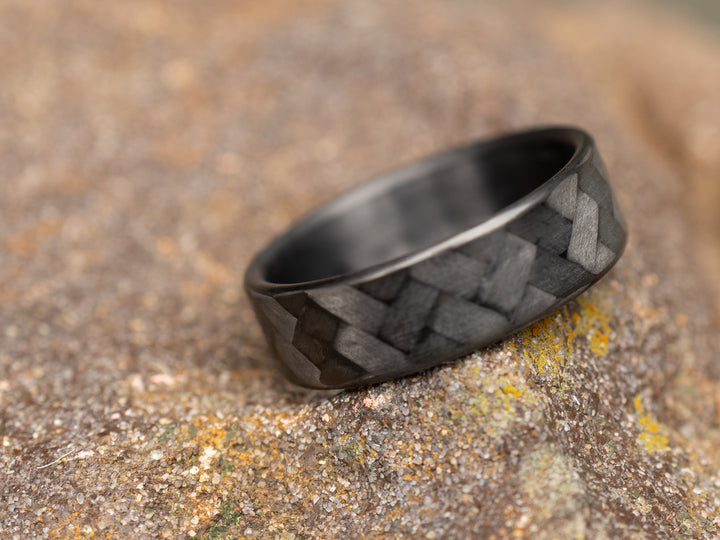 6mm carbon fiber ring with 45° twill pattern resting on textured stone surface outdoors