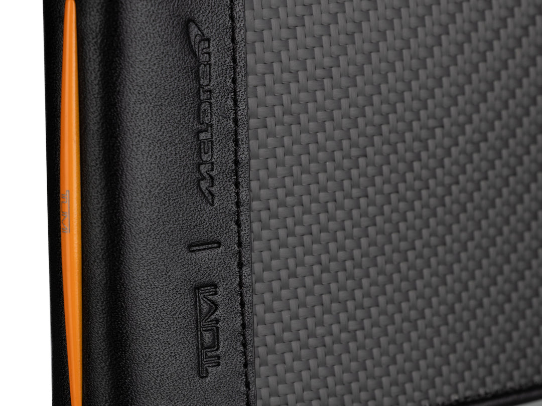 Angled view of TUMI McLaren carbon fiber wallet highlighting its 3K weave and orange leather edge accents