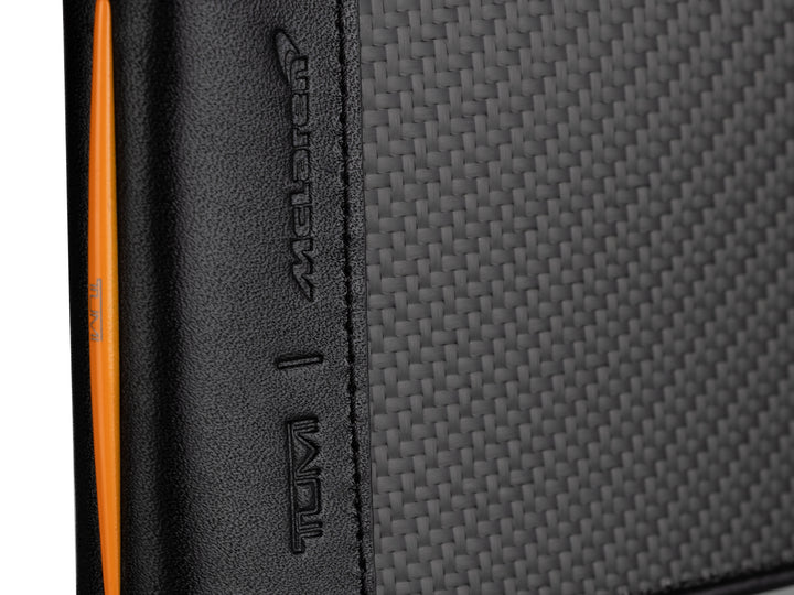 Angled view of TUMI McLaren carbon fiber wallet highlighting its 3K weave and orange leather edge accents