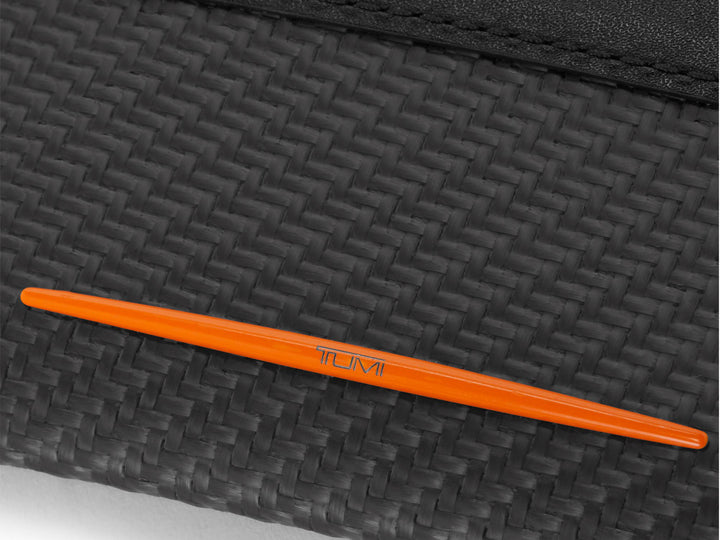 Close-up of the CX6 carbon fiber texture on TUMI | McLaren Card Case with orange Papaya accent.