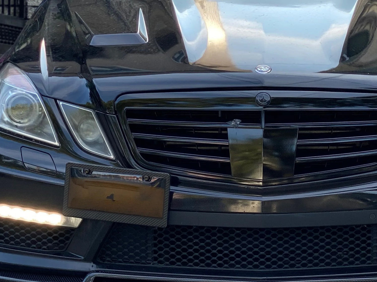 Carbon fiber license plate frame with smoked window installed on black luxury vehicle front bumper