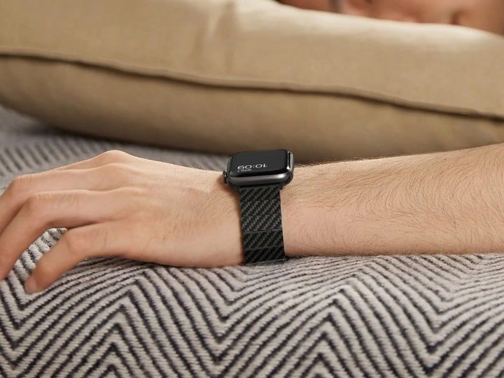 Person resting on a sofa wearing an Apple Watch with a sleek carbon fiber band.