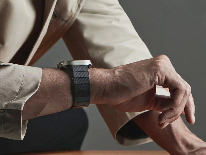 Close-up of a man's wrist with an Apple Watch featuring a stylish carbon fiber band, accentuating a professional look.