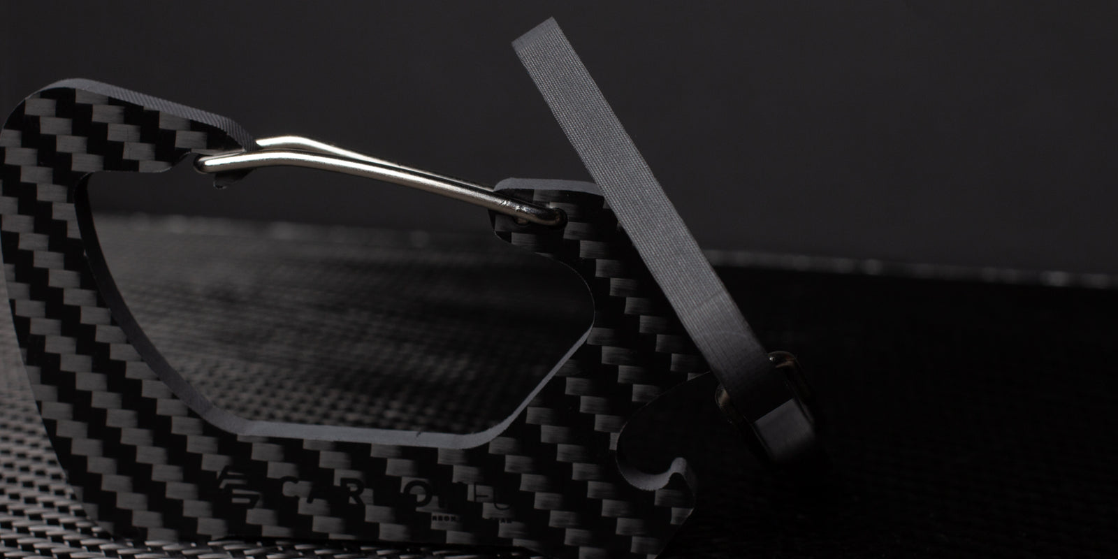 Side view of the CarbonFG Carabiner Bottle Opener showing its 6mm thickness and the durable twill weave carbon fiber pattern.