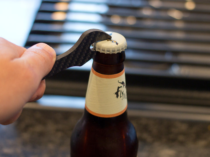 The carbon fiber wrench bottle opener in use, effortlessly opening a bottle cap with its sturdy design.