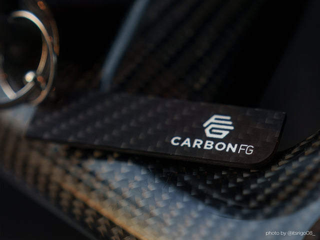 "Minimalist matte solid carbon fiber key tag with subtle 3K weave detail and CarbonFG logo on a carbon fiber surface