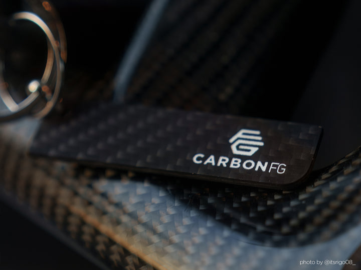 "Minimalist matte solid carbon fiber key tag with subtle 3K weave detail and CarbonFG logo on a carbon fiber surface