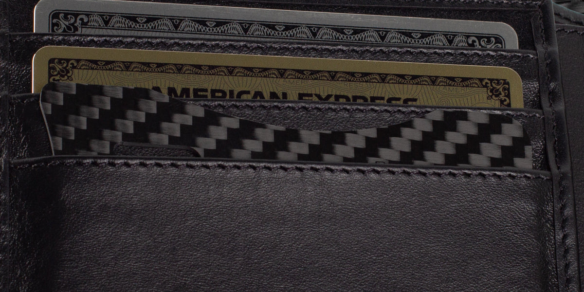 A slim CarbonFG Carbon Fiber Credit Card Bottle Opener snugly inserted in a wallet slot next to credit cards, showcasing its convenient size and stylish carbon fiber weave.