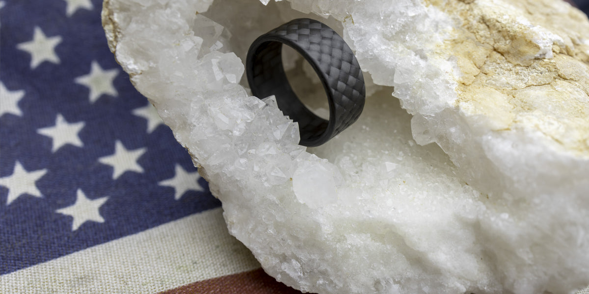 WeaveForce Vertex carbon fiber ring displayed inside a quartz crystal geode with an American flag in the background, symbolizing USA craftsmanship and strength.