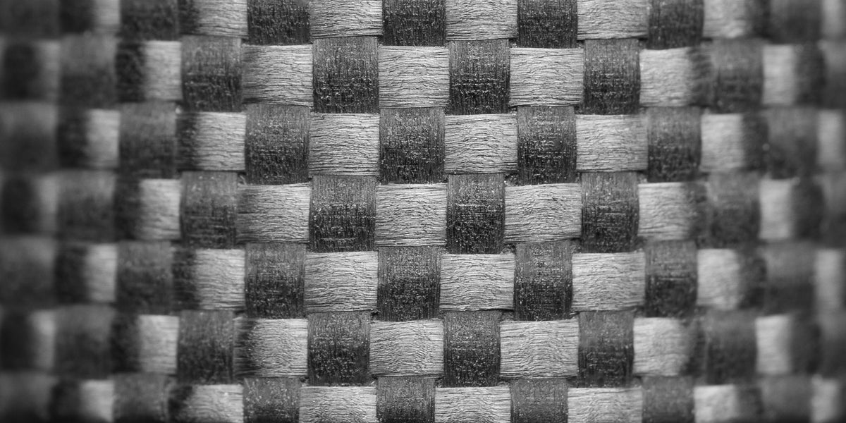 Extreme close-up of 1K carbon fiber weave used in the Gridlock ring, revealing the detailed basketweave texture and fine craftsmanship