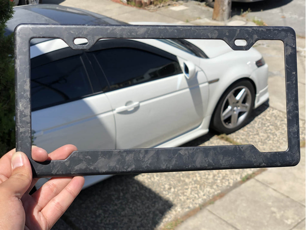 Forged Carbon Fiber License Plate Frame - 2 Holes Angled Bottom - Matte Finish being held by customer