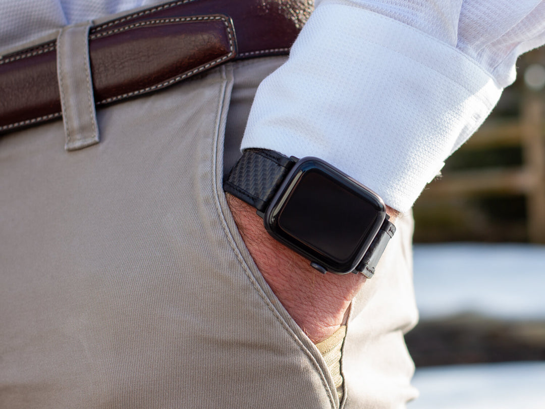CarboBand carbon fiber and leather Apple Watch strap styled with business attire on a man's wrist.