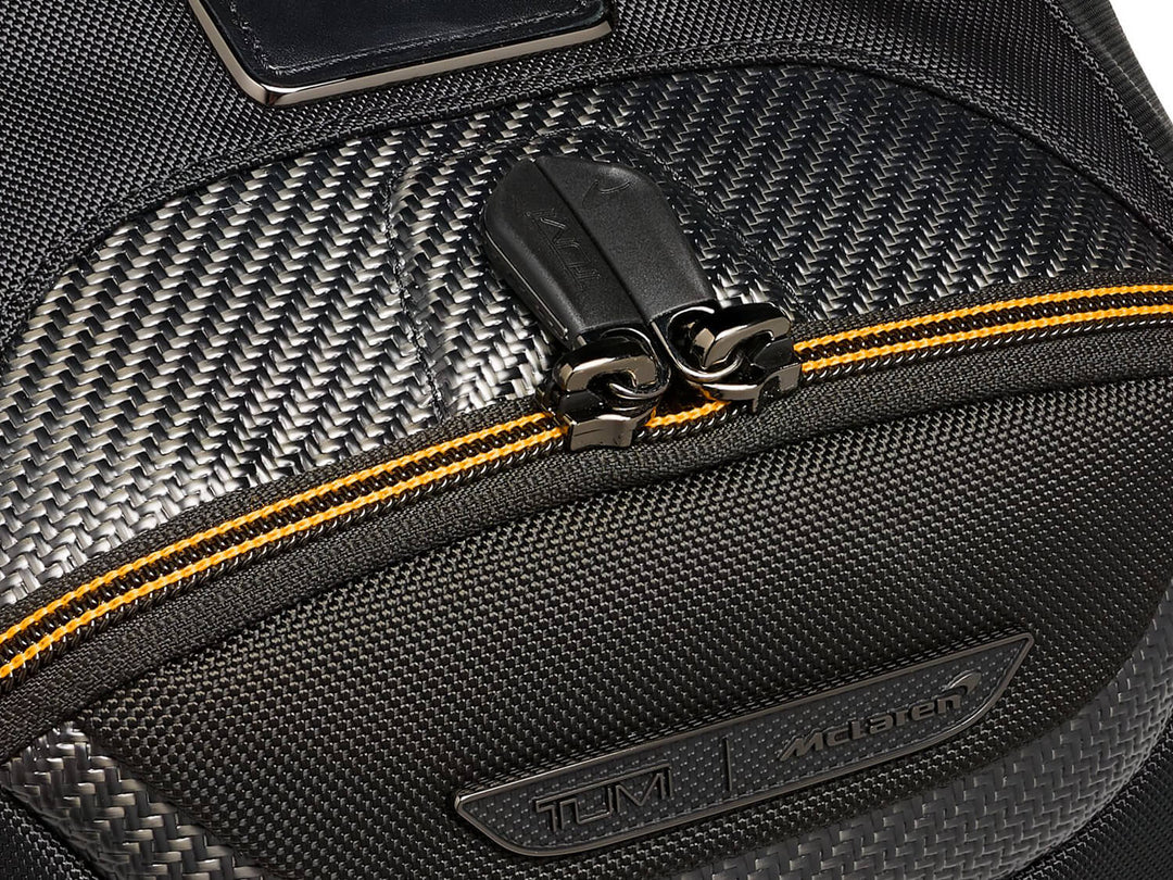 Close-up of the TUMI | McLaren Velocity Backpack's zipper and carbon fiber accents, highlighting luxury materials.